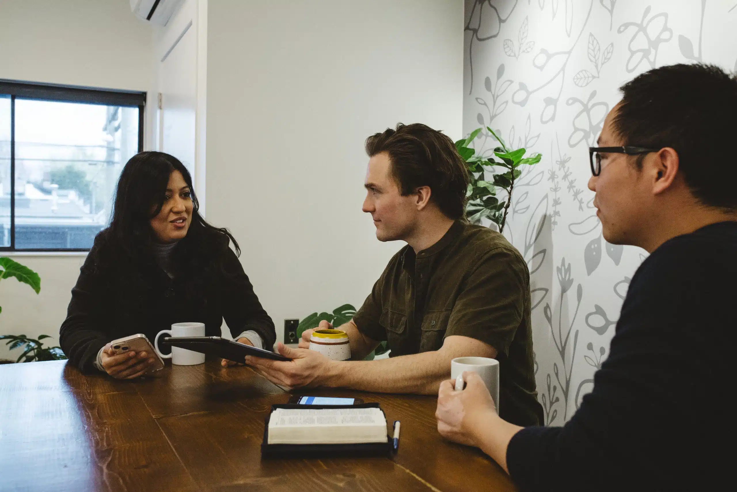 3 people at a coffee shop discuss The Sanctuary Course