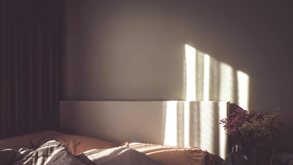 bed in front of wall with sunlight