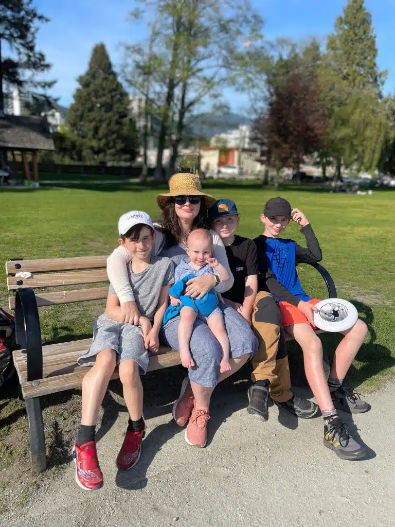 Bryana sits on a bench with her four boys