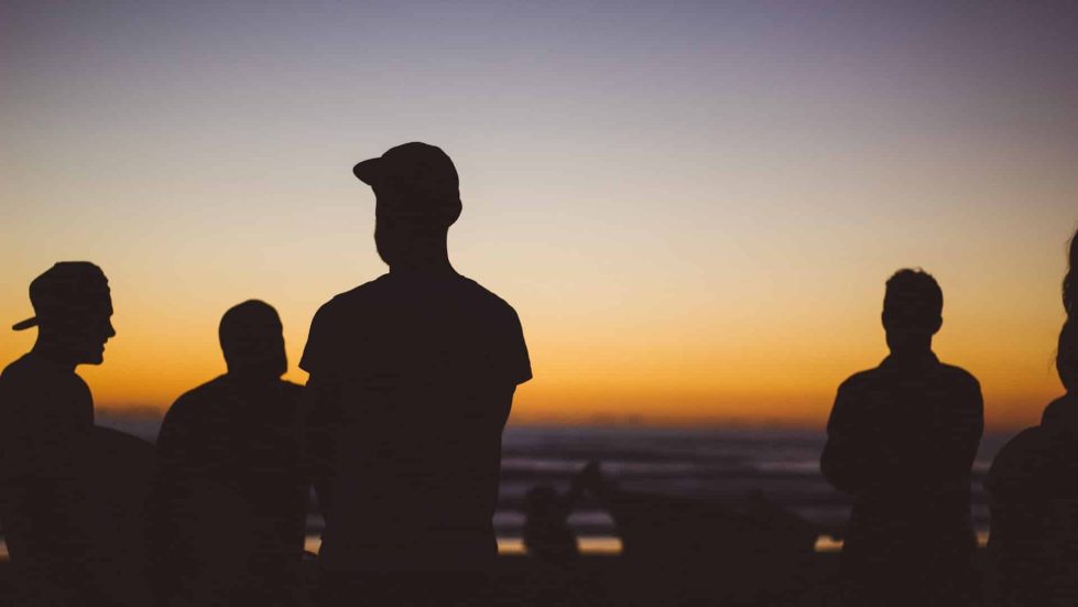 group of men silhouetted by sunset or sunrise