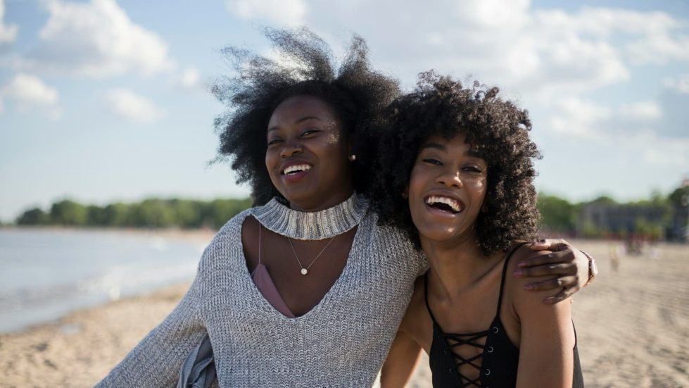 2 black women laughing with arms around each other