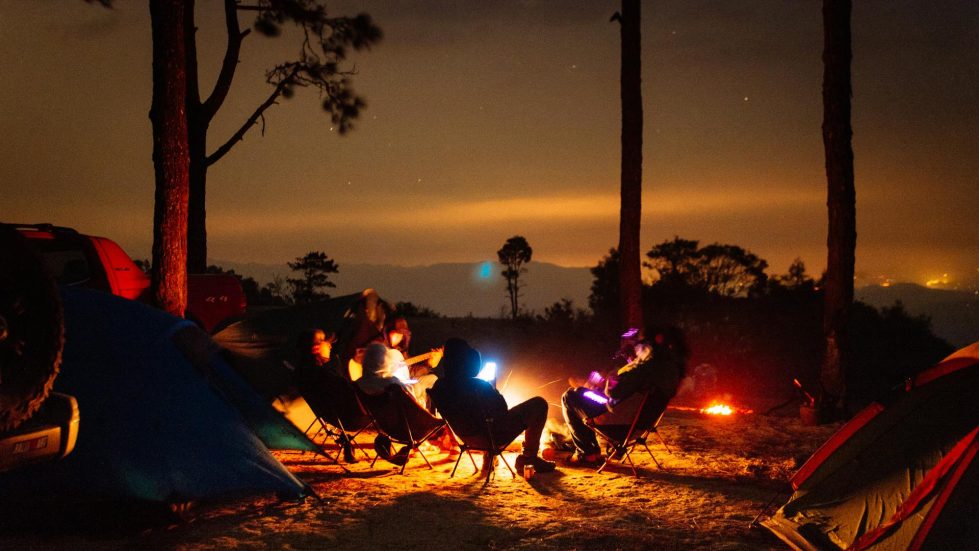 Friendship-Men sitting among a campfire while the embers and LED lights glow